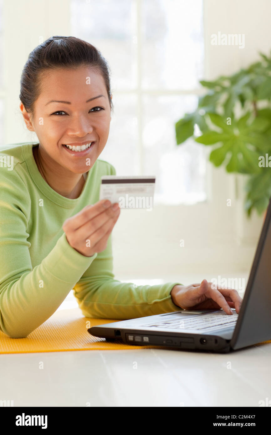 Smiling young Asian woman shopping online with credit card and laptop computer Stock Photo
