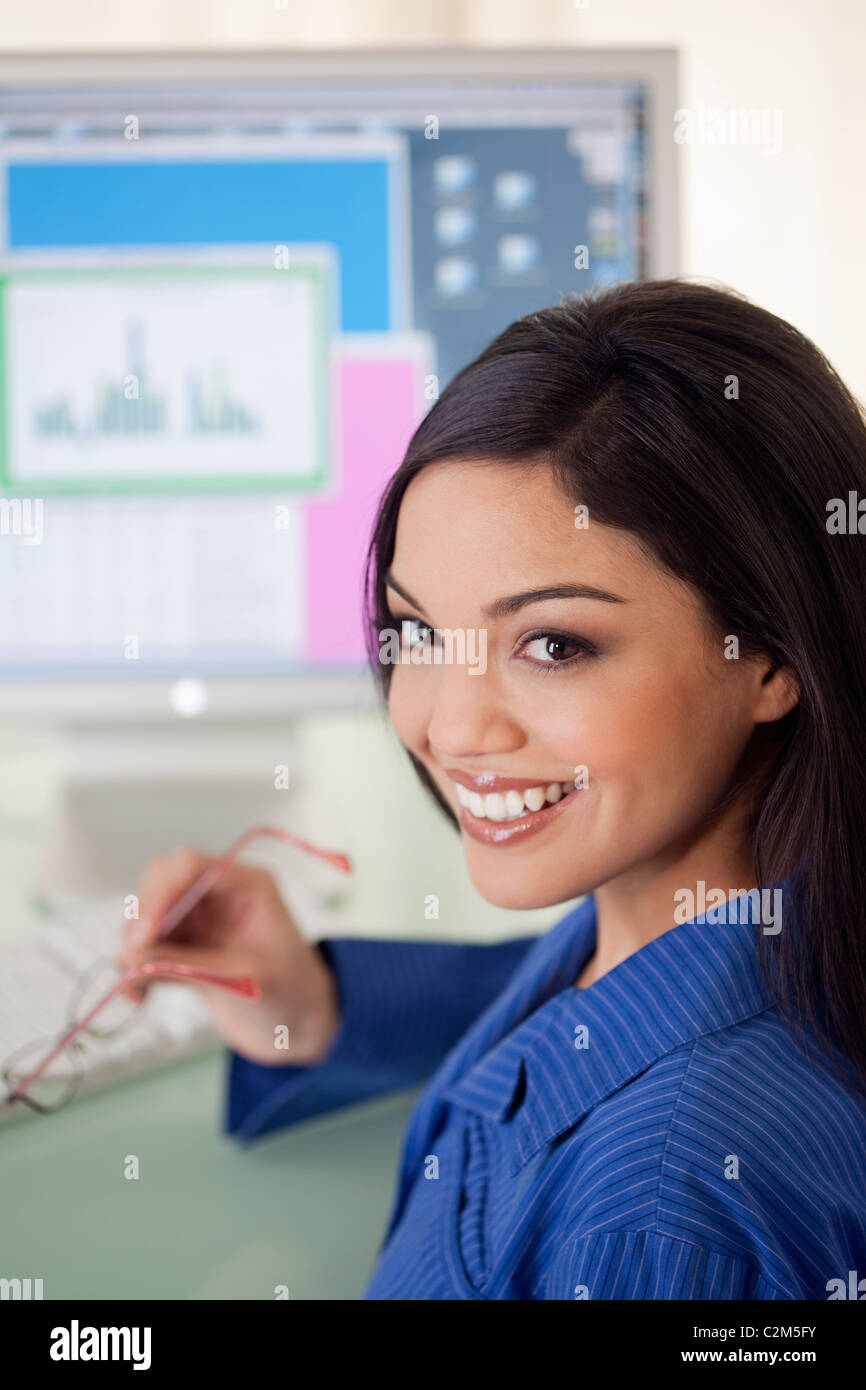 Smiling Hispanic woman at office desk with computer monitor Stock Photo Alamy