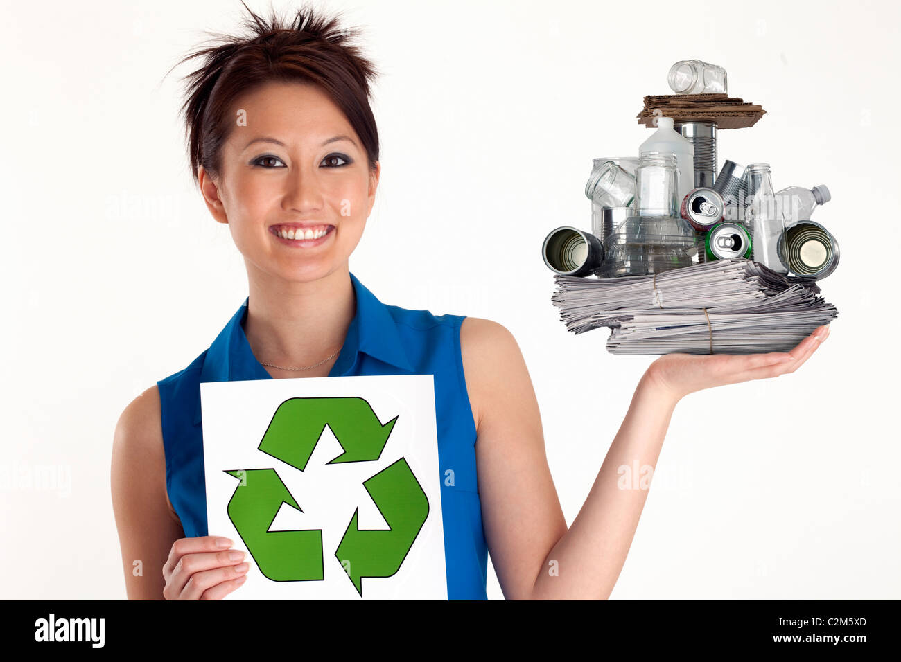 Pretty Asian Woman holding up a Recycle sign and recyclables Stock Photo