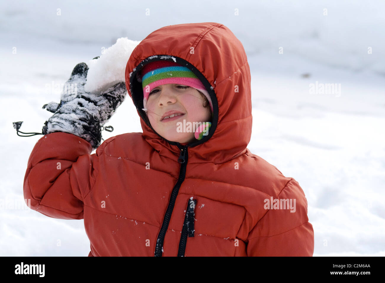 Girl age  7 attempting to throw snowball winter in a city park. St Paul Minnesota MN USA Stock Photo