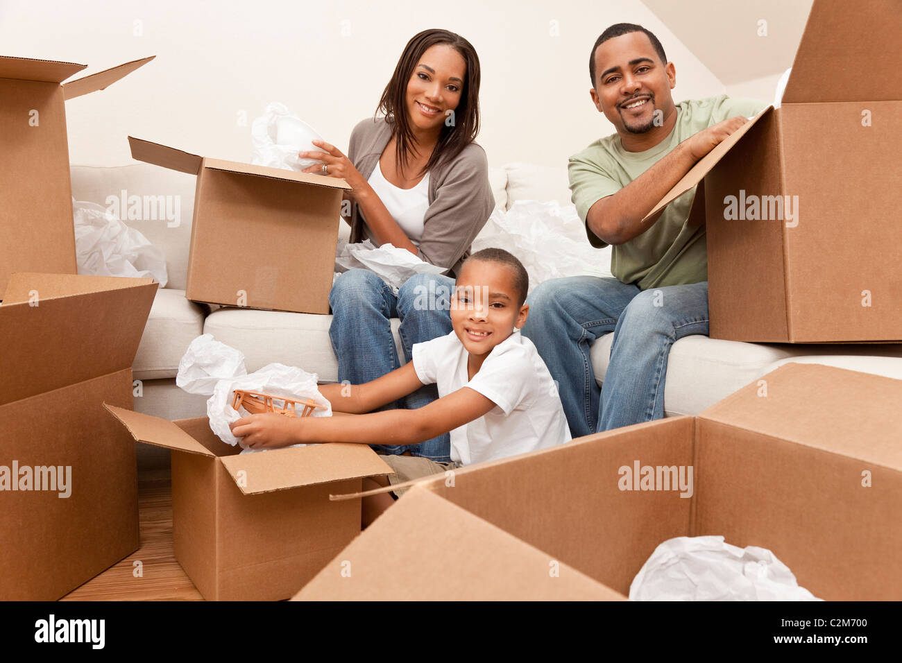 African American family, parents and son, unpacking boxes and moving into a new home Stock Photo