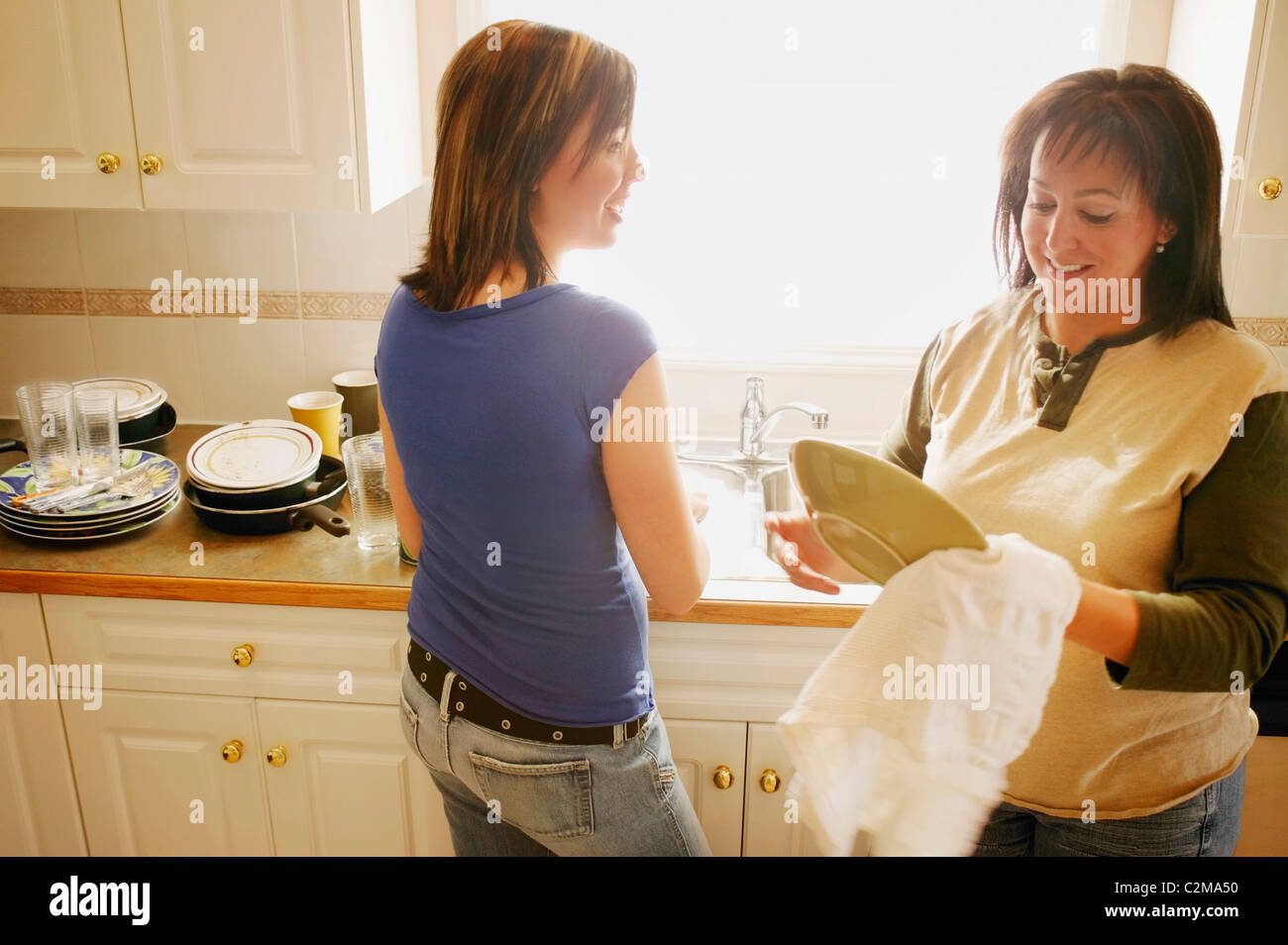 Mother And Daughter Doing Dishes Together Stock Photo