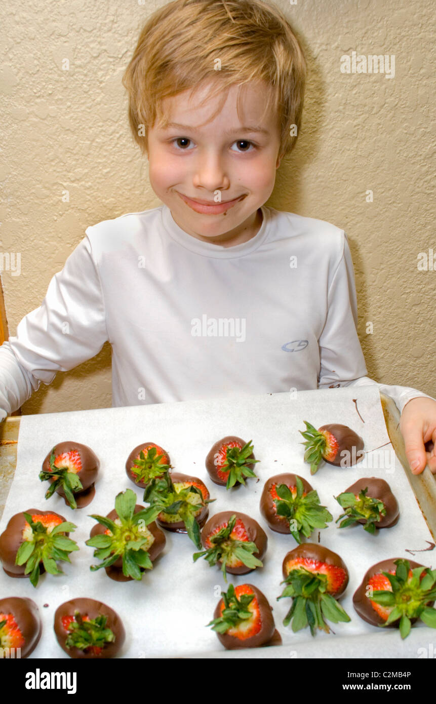 Boy age 8 with his tray of chocolate dipped strawberries on parchment