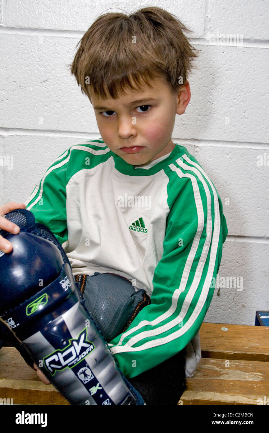 Boy age 5 getting dressed for a hockey game looking angry. St Paul