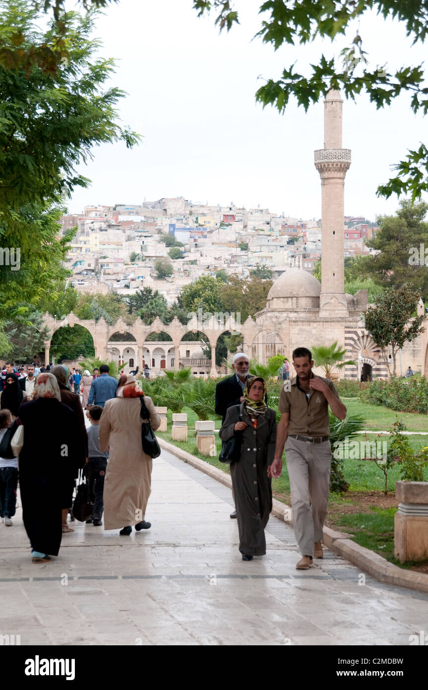 Visitors and pilgrims stroll near the edge of the pond of sacred fish (balikligul) and the Cave of Abraham, in Urfa, in southeastern Turkey. Stock Photo