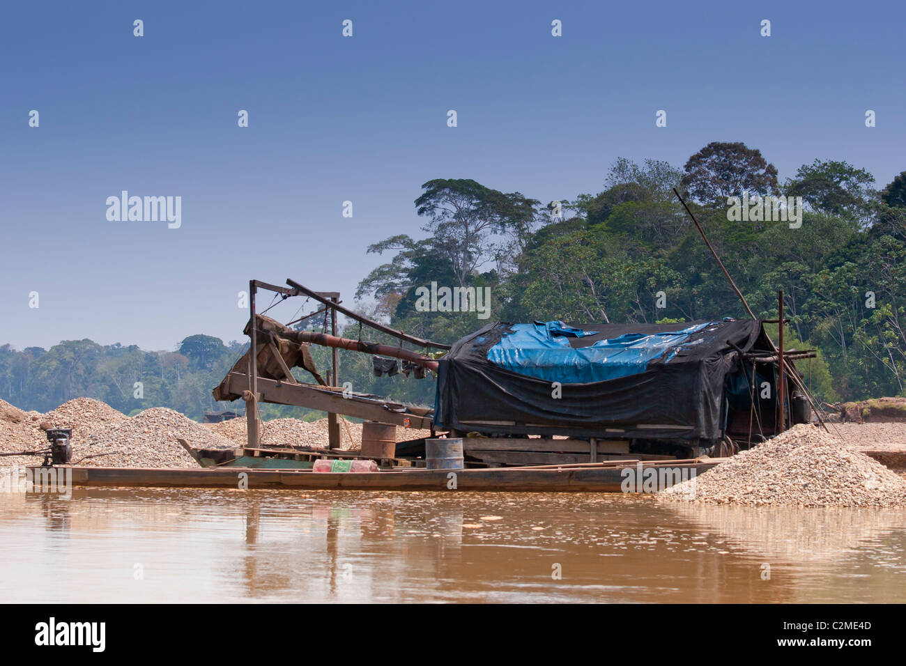 Illegal gold mining on the Tambopata River in the Peruvian Amazon. Boats mine the alluvial sand for gold and release mercury. Stock Photo
