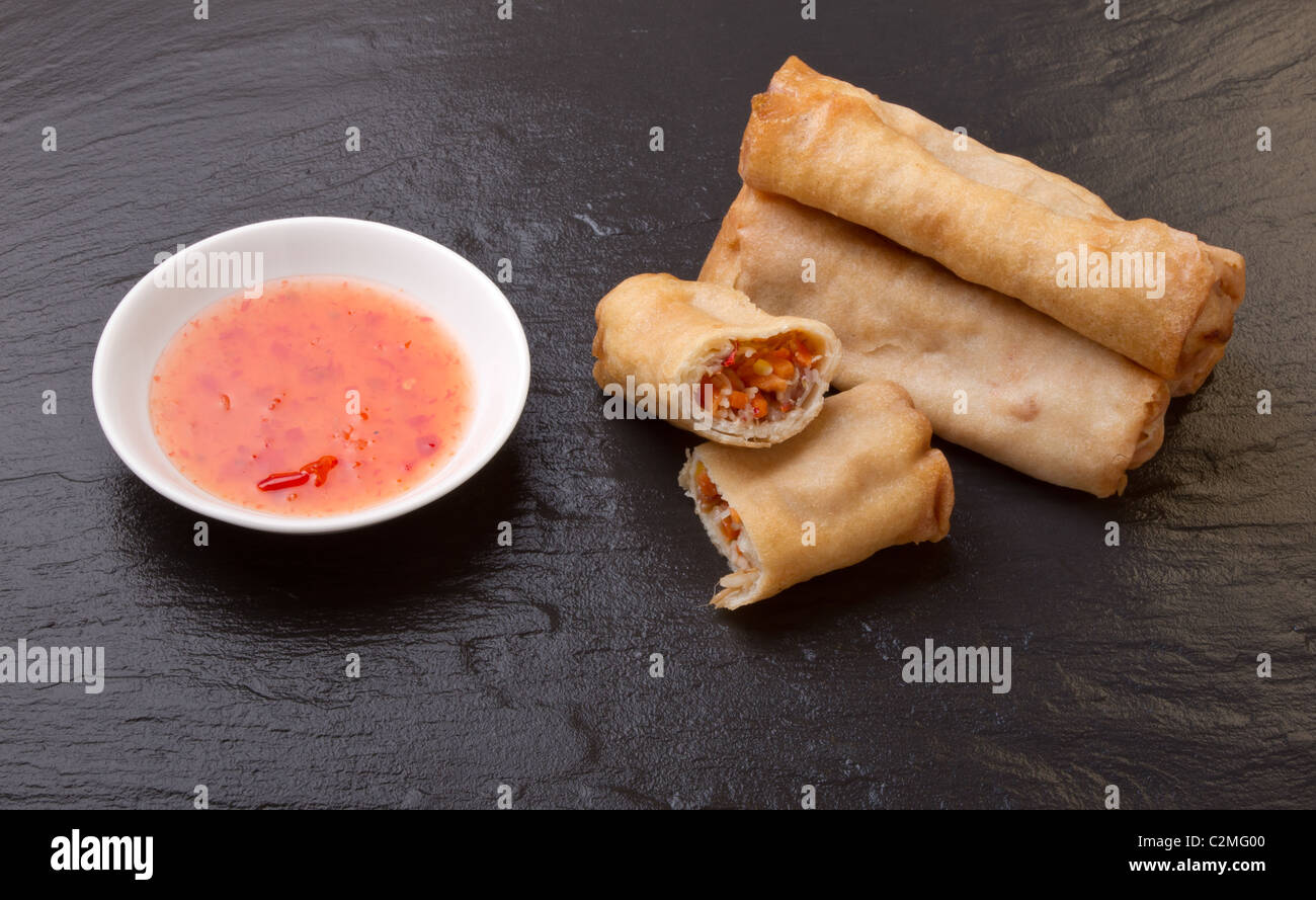 Spring rolls with sweet chili dipping sauce on dark grey slate