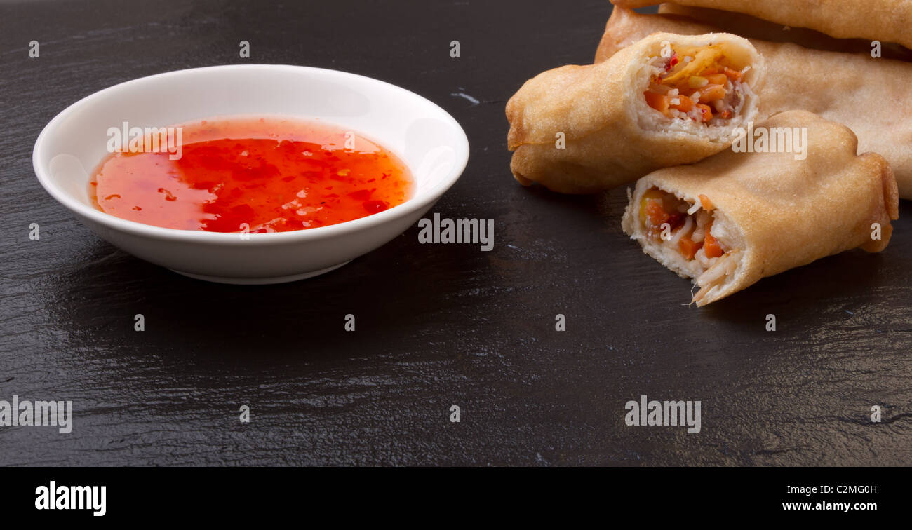 Spring rolls with sweet chili dipping sauce on dark grey slate