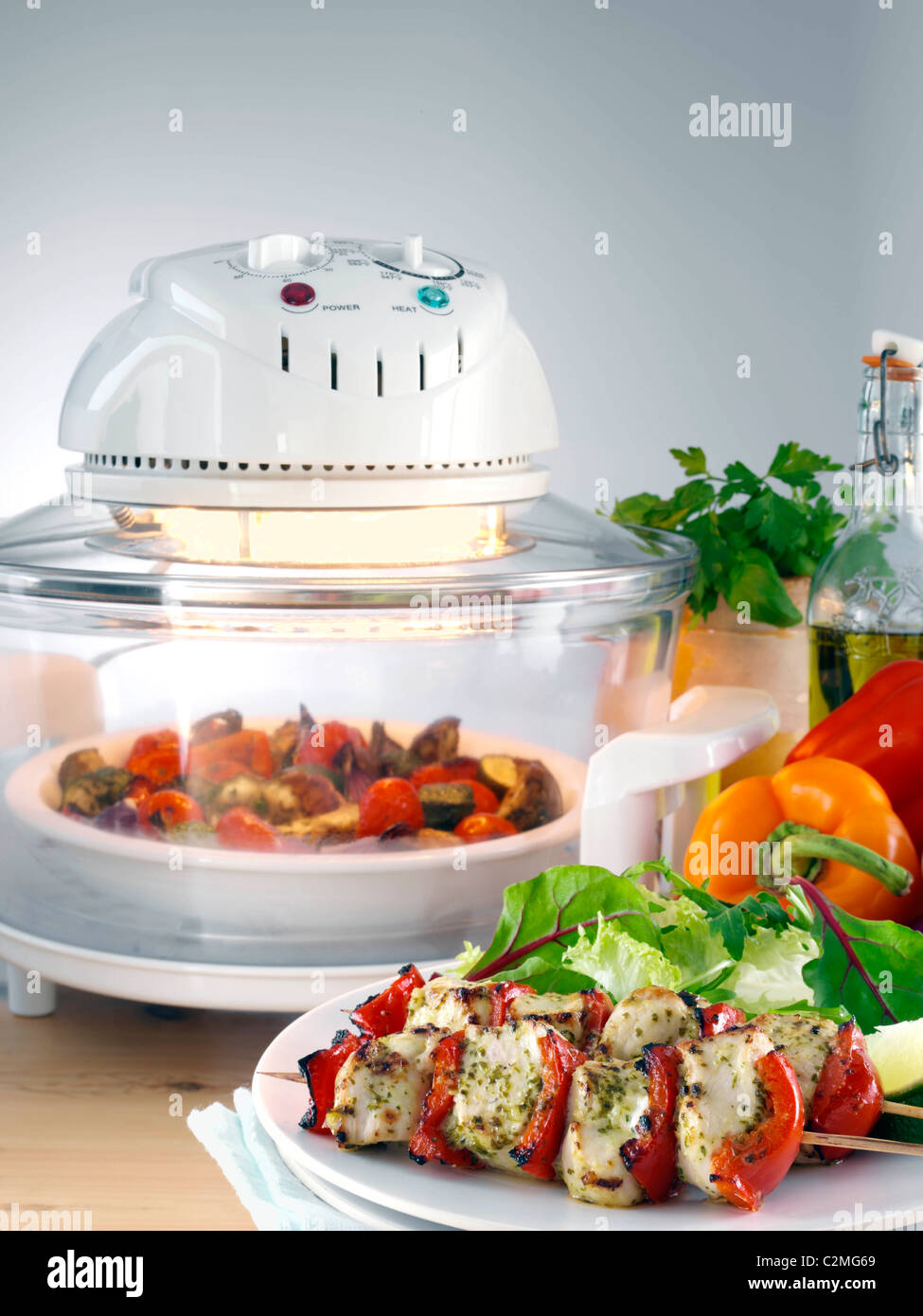 Halogen oven with roast vegetables a plate with chicken kebabs and