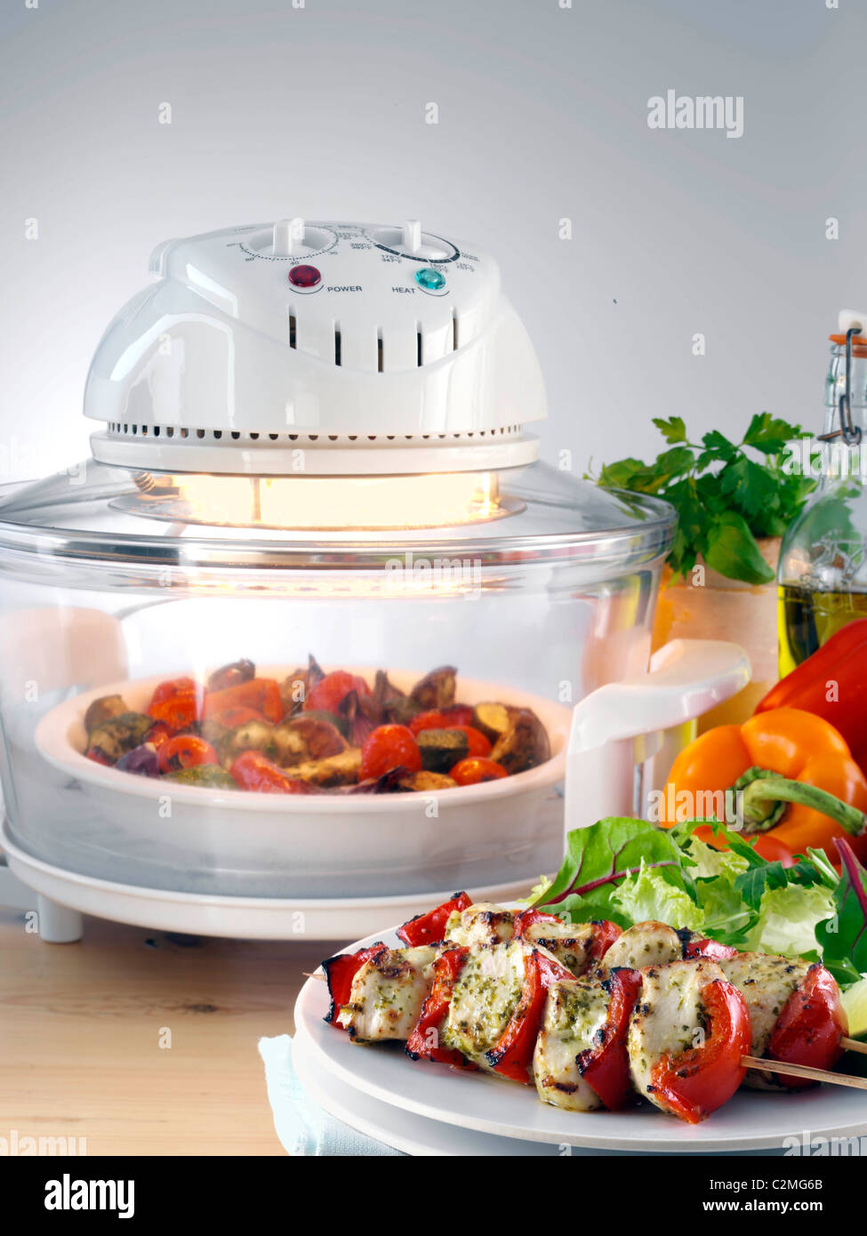 Halogen oven with roast vegetables a plate with chicken kebabs and
