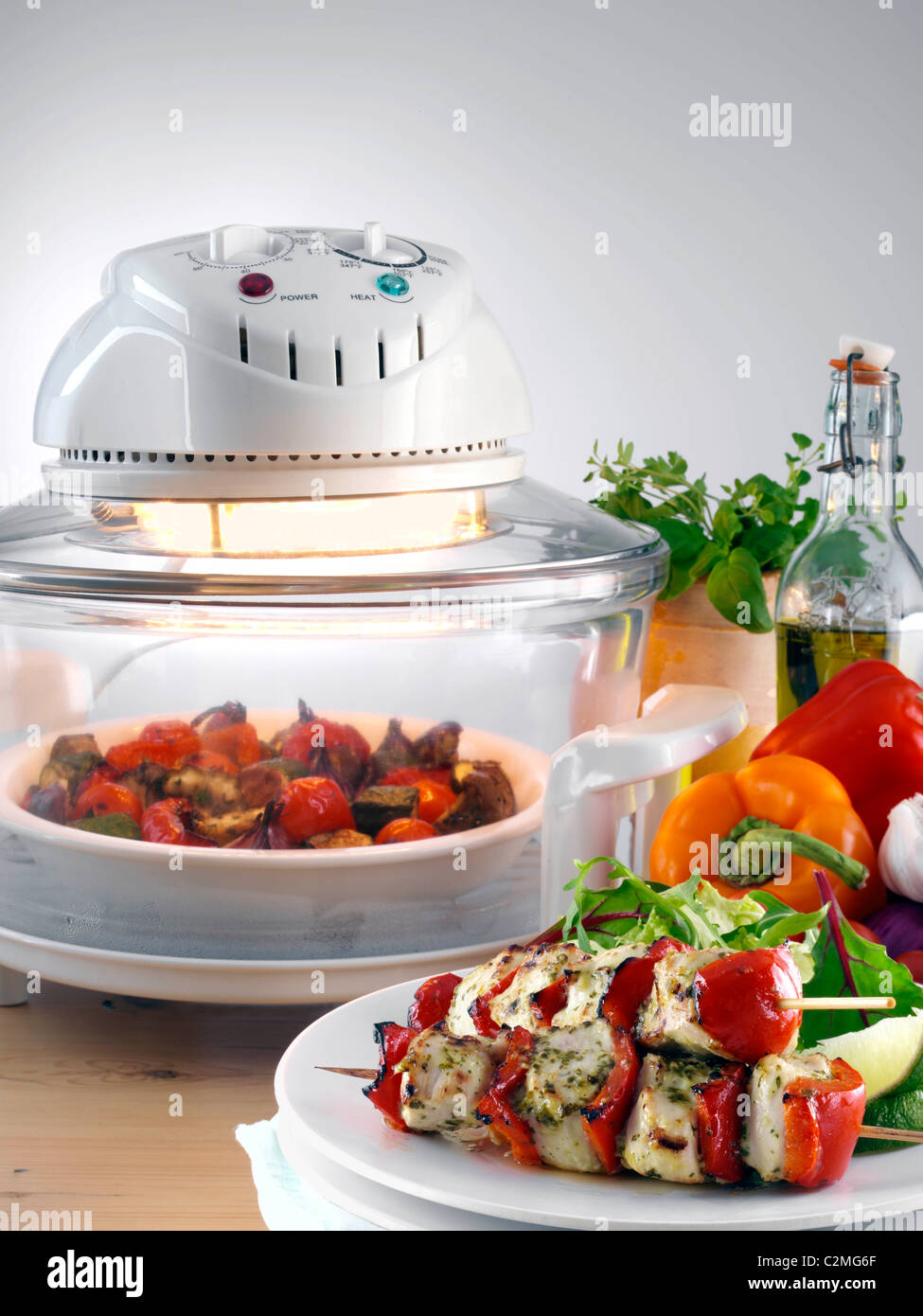 Halogen oven with roast vegetables a plate with chicken kebabs and