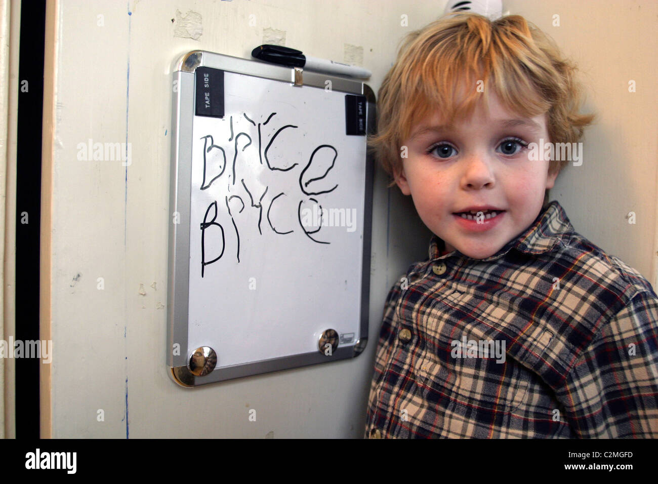 5 Year Old Boy Writing His Name On The Blackboard In The Kitchen Stock