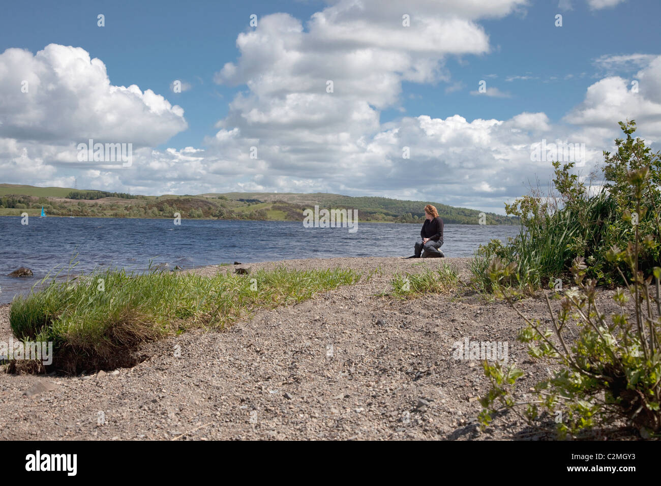 Woman Sitting On The River's Edge, Dumfries And Galloway, Scotland Stock Photo