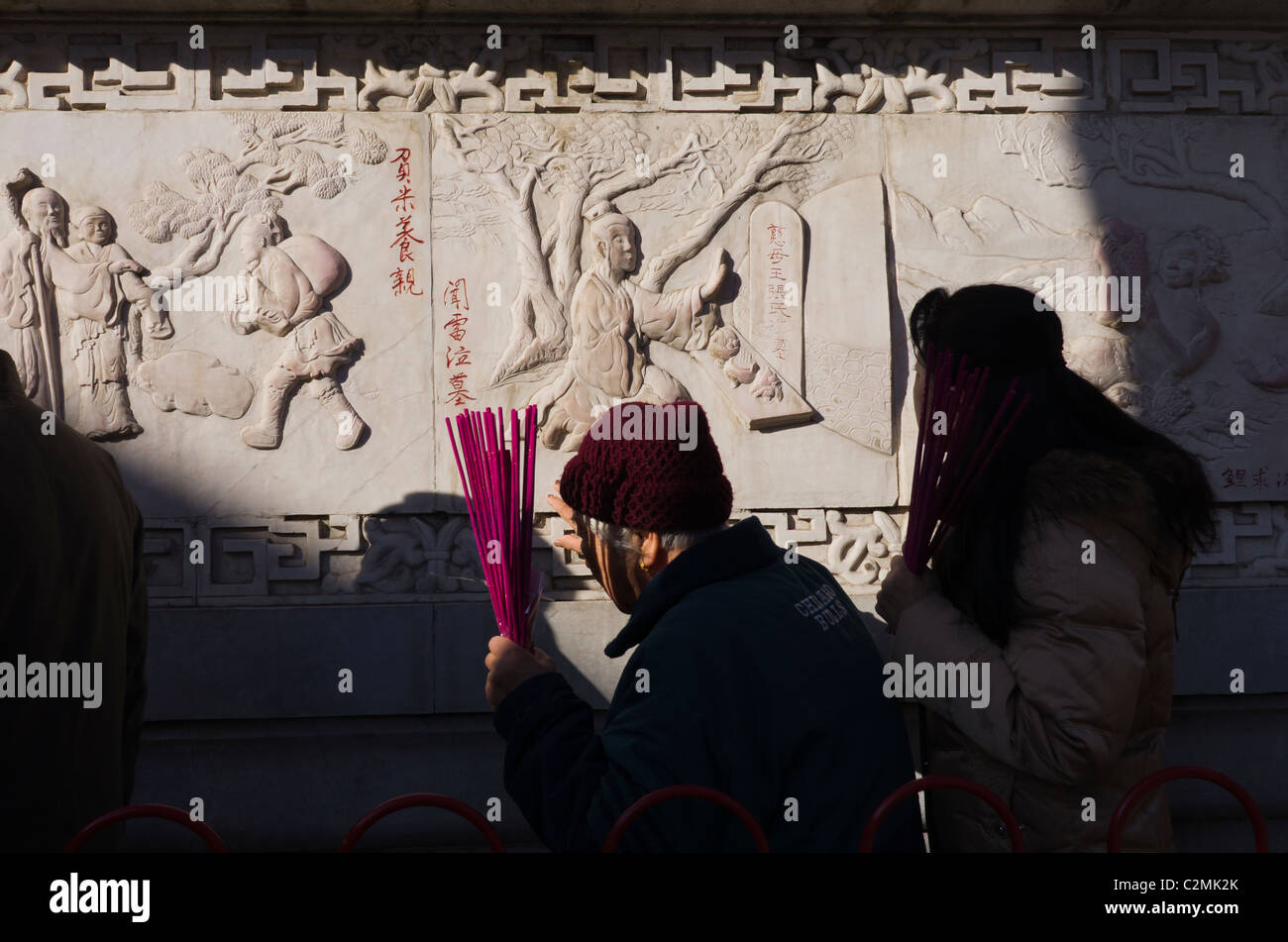 Worshippers touching a wall with Zodiac Animals for good luck. The White Cloud Temple. Beijing. China Stock Photo