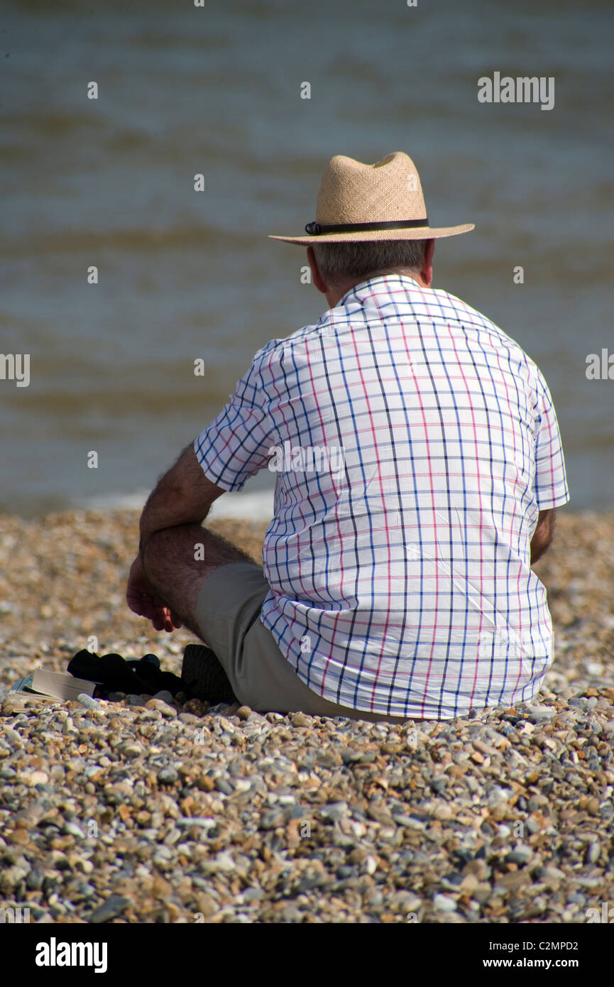 older man sitting alone on beach Stock Photo