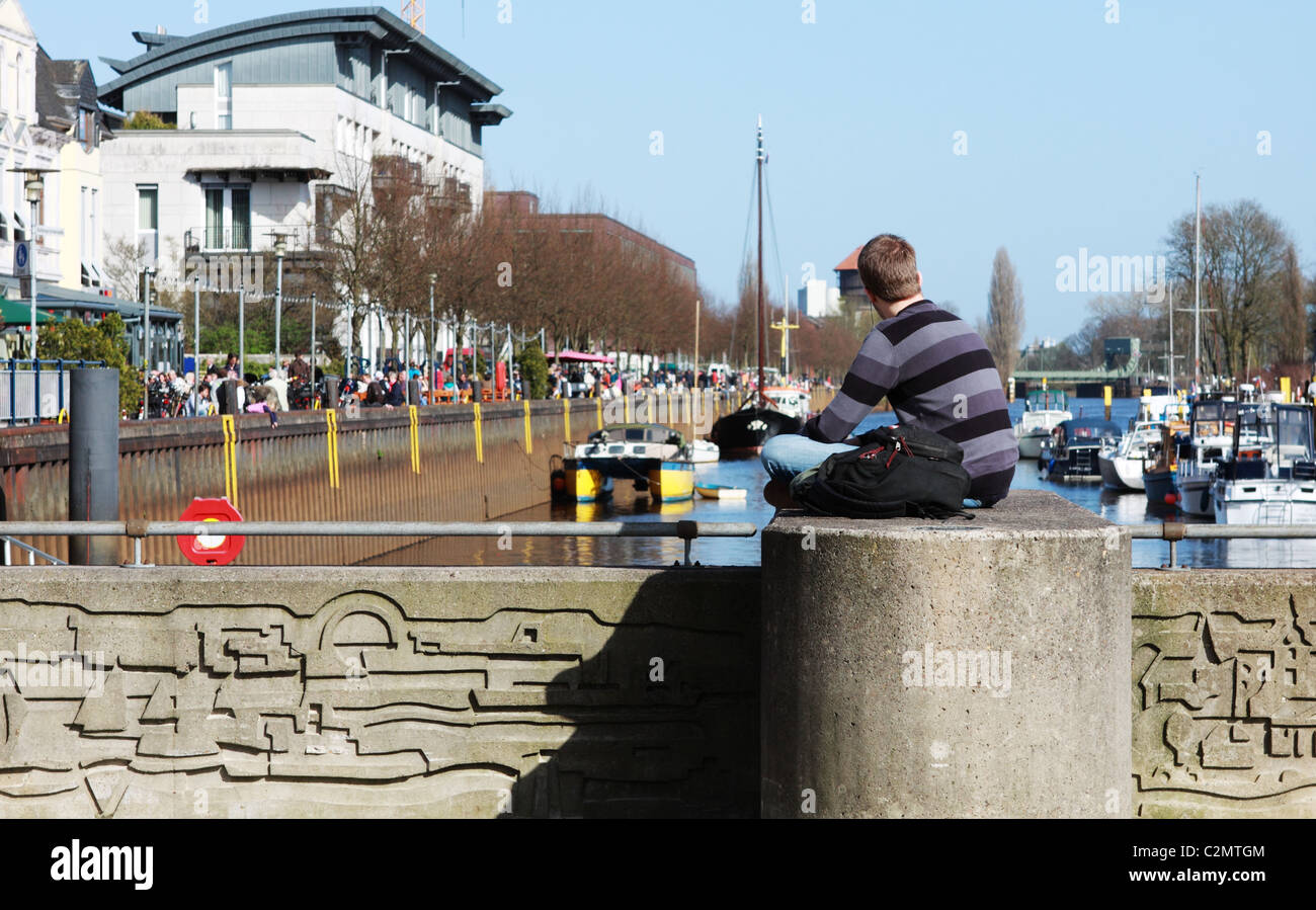 young guy is listening to music and looking on the river Stock Photo