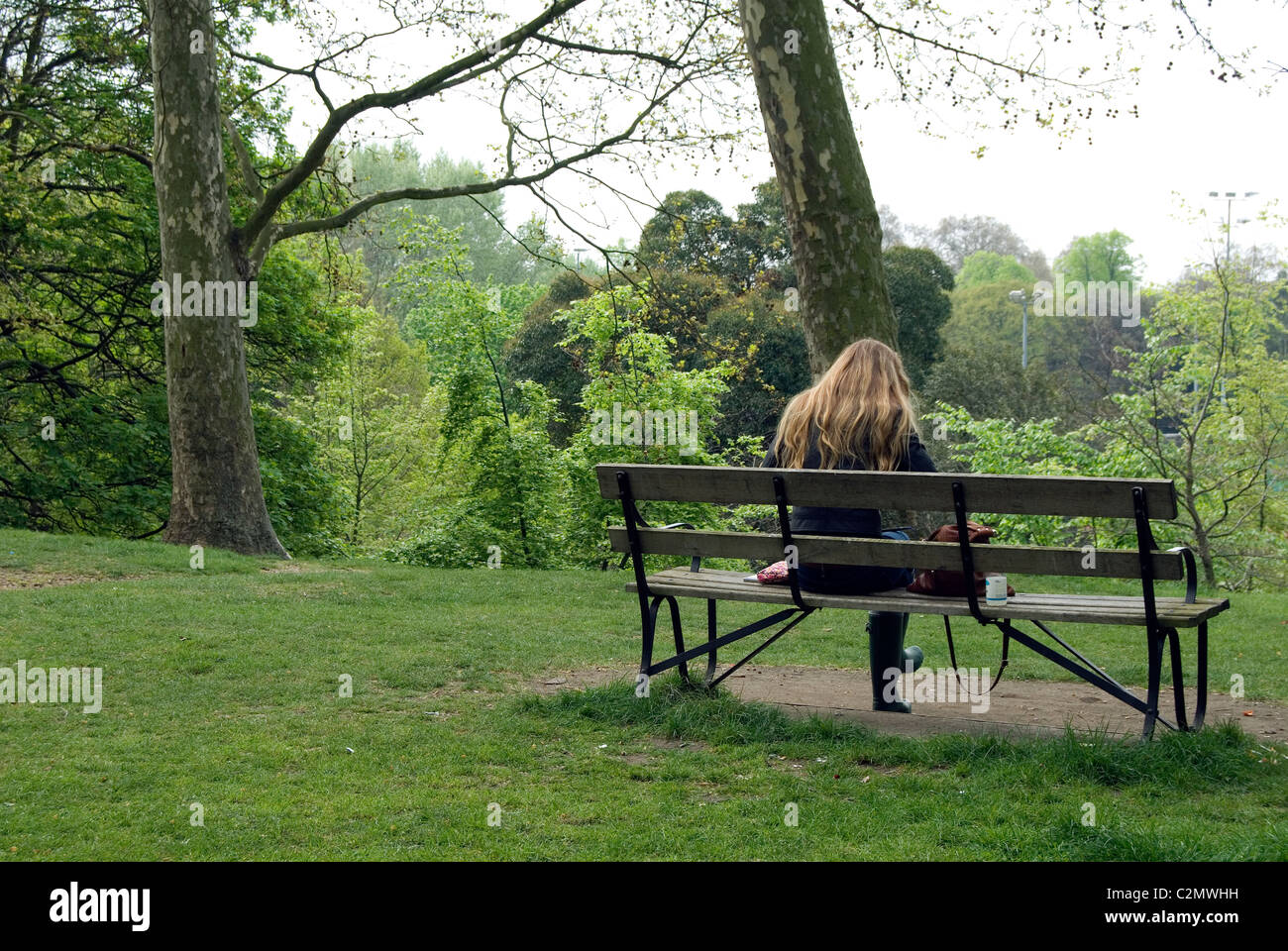 Woman sitting in a bench in a park Stock Photo - Alamy