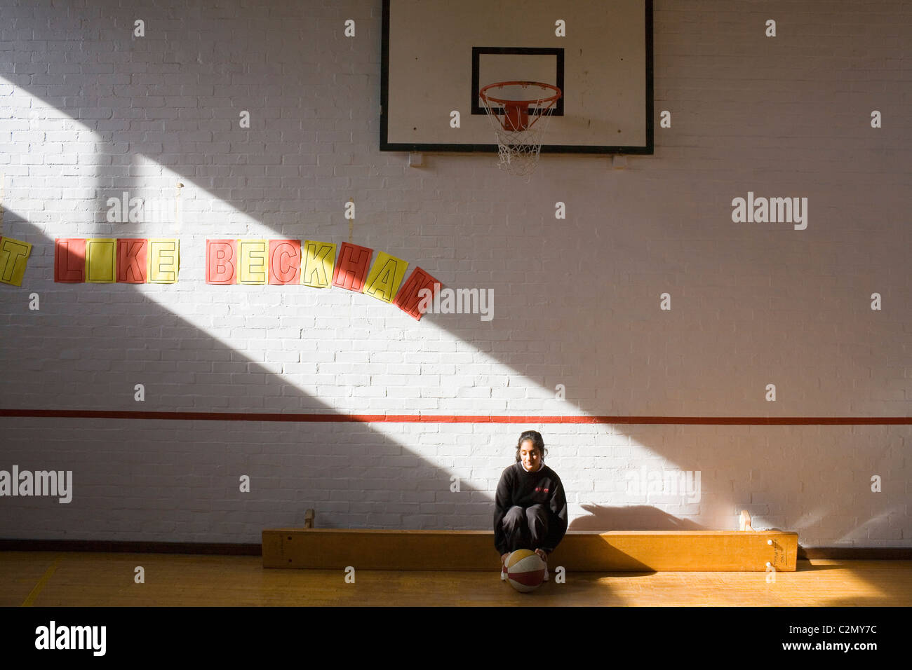 A Hindu Girl Sat On A Bench With A Basketball In The School Gym