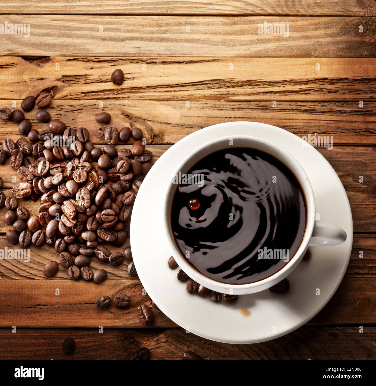 Drop falling into a cup of coffee. On a wooden background Stock Photo