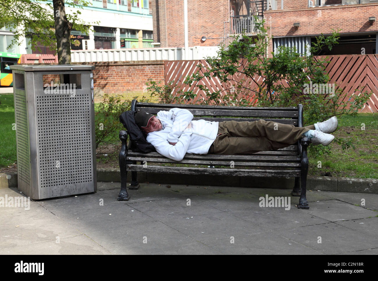 A man asleep on a bench in a U.K. city. Stock Photo