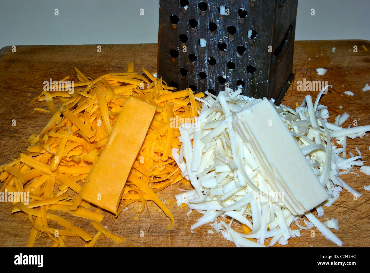 https://c8.alamy.com/comp/C2N1HC/grater-grated-cheddar-mozarella-cheeses-wooden-cutting-board-C2N1HC.jpg