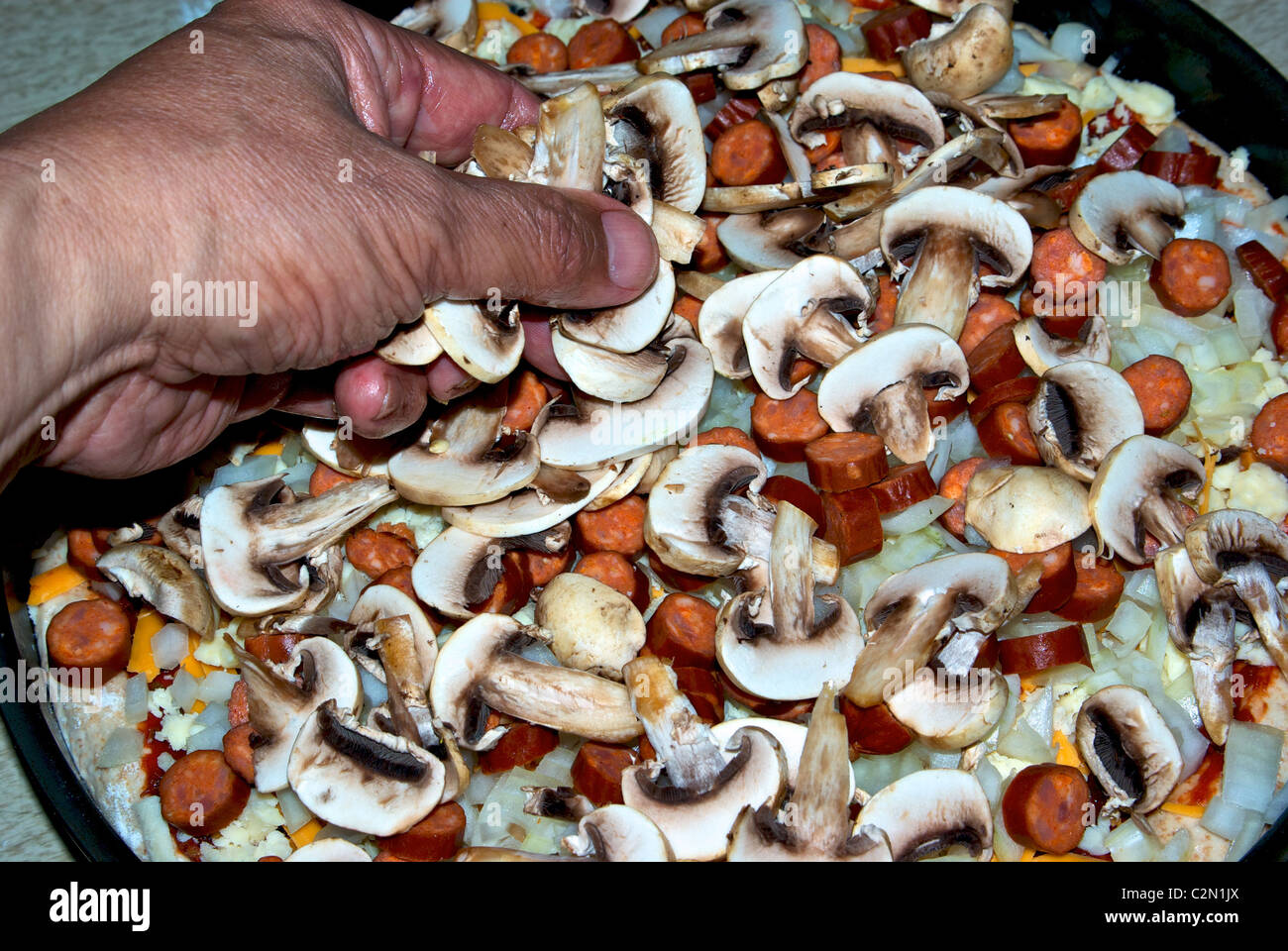 Spreading mushroom slices over grated cheese diced chopped onion on