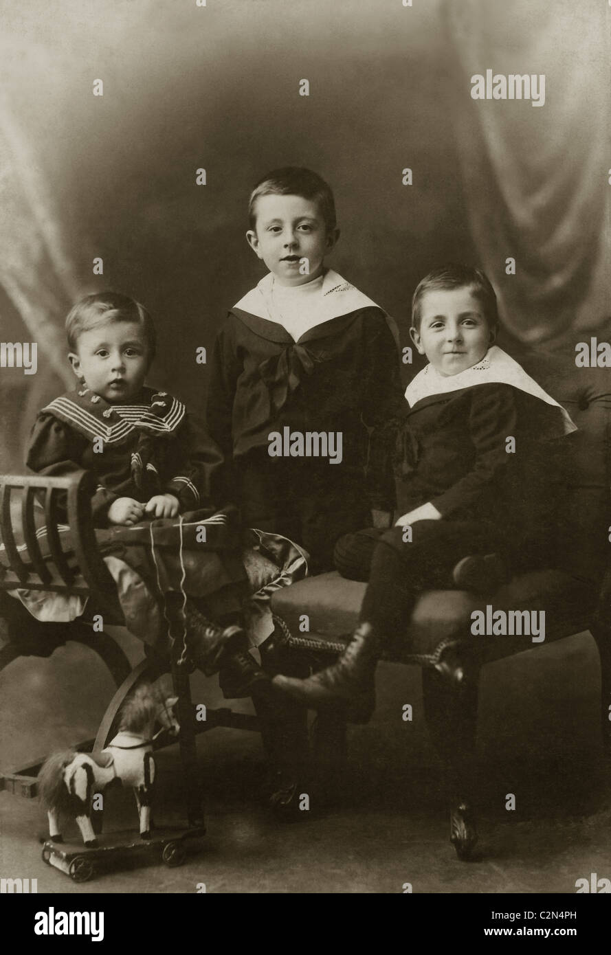 Studio portrait of three smartly dressed young Victorian boys, brothers, siblings,  wearing sailor suits with a toy wooden horse, circa 1890's, Eccles, Lancashire, U.K. Stock Photo
