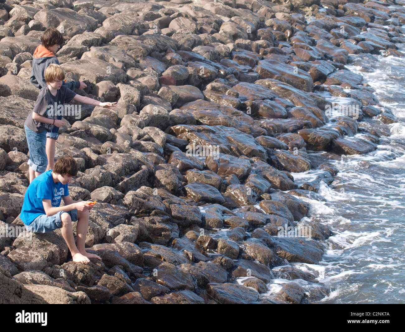 Three boys fishing with hand lines, Bude, Cornwall, UK Stock Photo