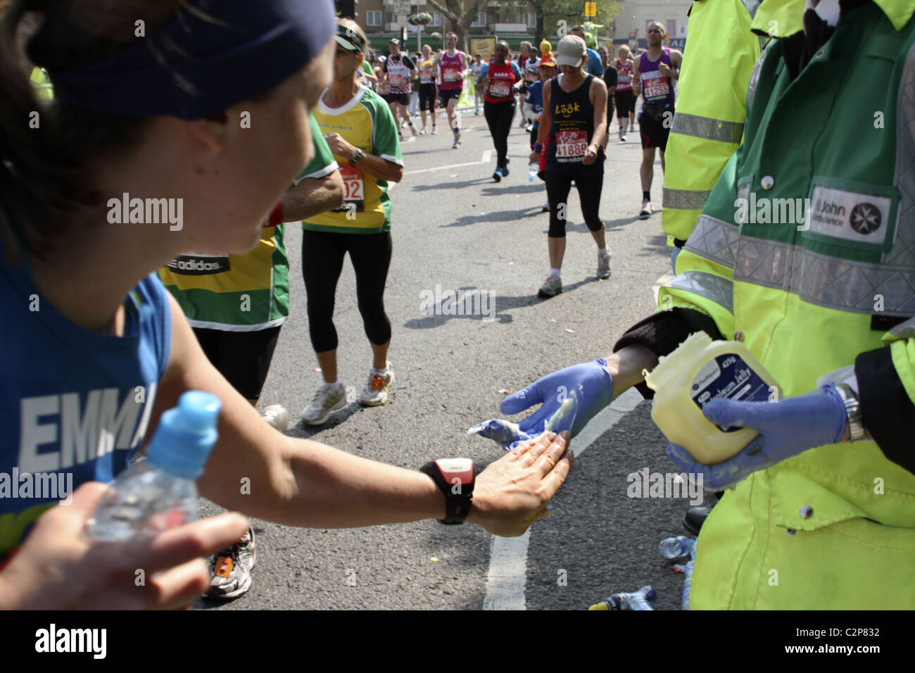 Runner accepts petroleum jelly from St John Ambulance volunteer on route of London Marathon Stock Photo
