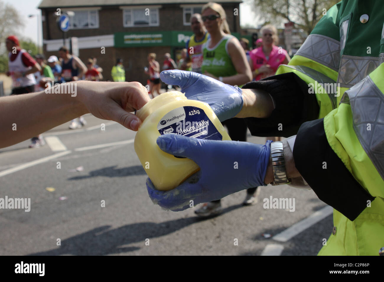 Runner accepts petroleum jelly from "St John's Ambulance" volunteer on
