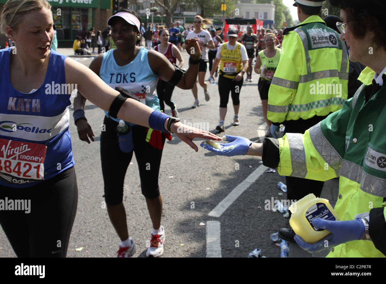Runner accepts petroleum jelly from "St John Ambulance" volunteer on