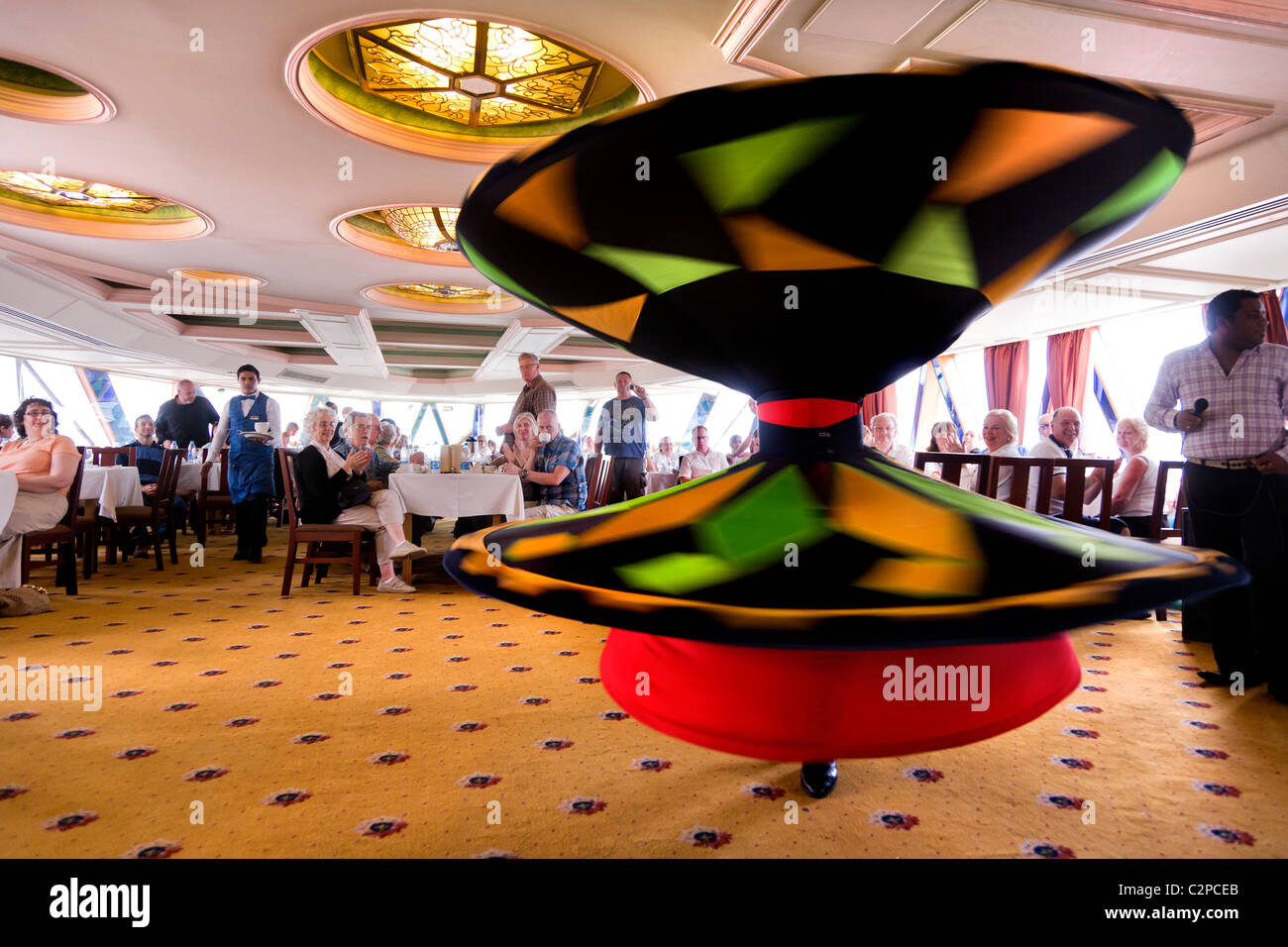 A WHIRLING DERVISH ENTERTAINING TOURISTS ON A NILE RIVER BOAT, Stock Photo