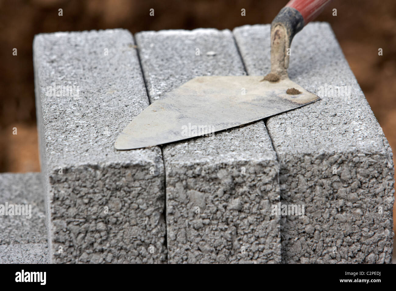 bricklaying trowel on a pile of half cement breeze blocks building a block retaining wall in the uk Stock Photo