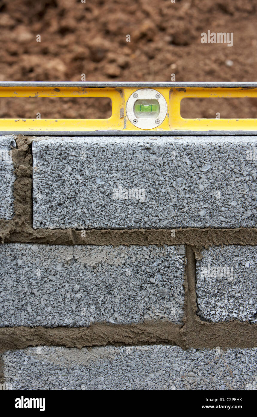 using a spirit level to check levels when building a block retaining wall in the uk Stock Photo