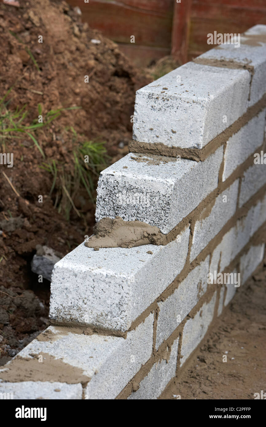 bricklaying wall with half cement breeze blocks building a block retaining wall in the uk Stock Photo