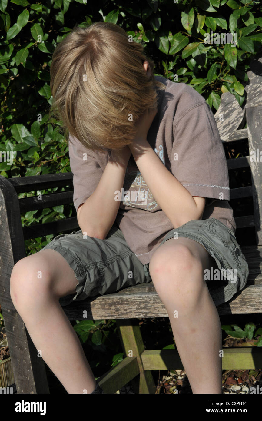 white blond-haired young boy looking sad and unhappy coping with loneliness during lockdown Stock Photo