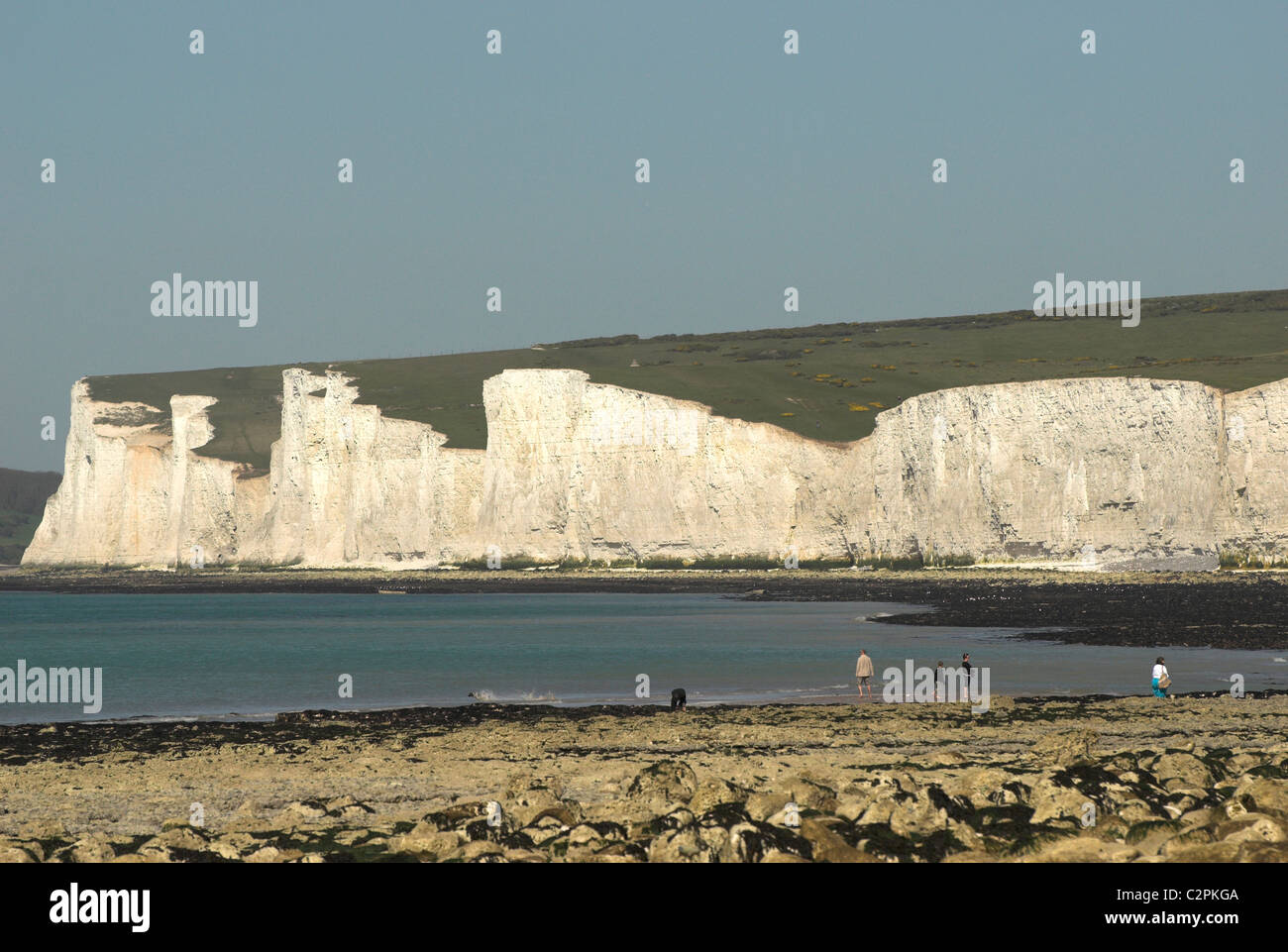 A family playing on the rocky beach at Birling Gap in the South Downs National Park with the Seven Sisters in the background. Stock Photo
