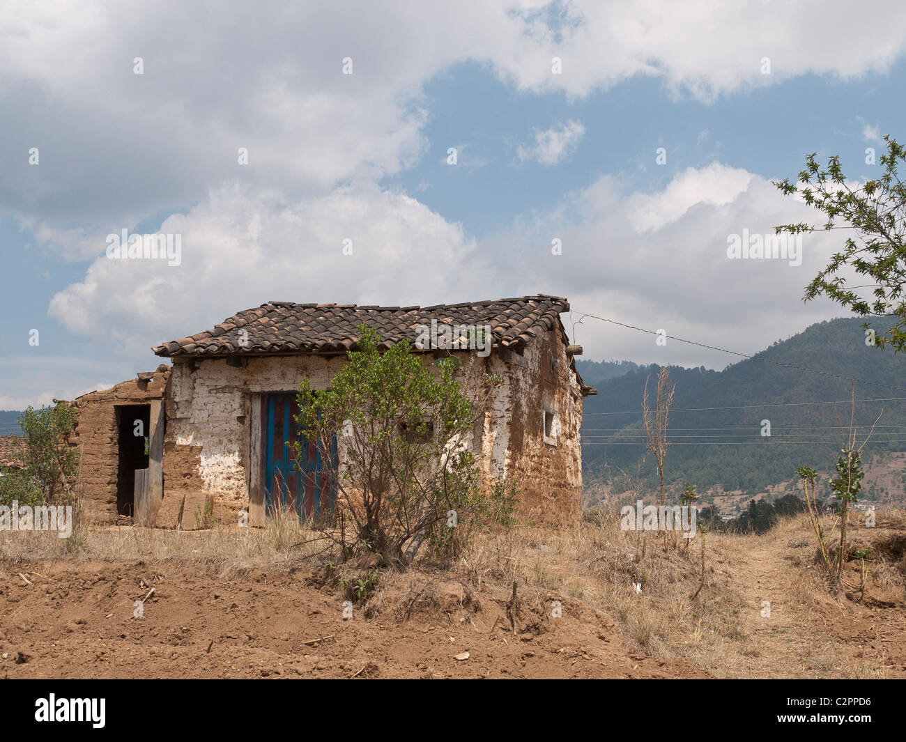 A tiny, modest adobe house situated on farmland in Totonicapan