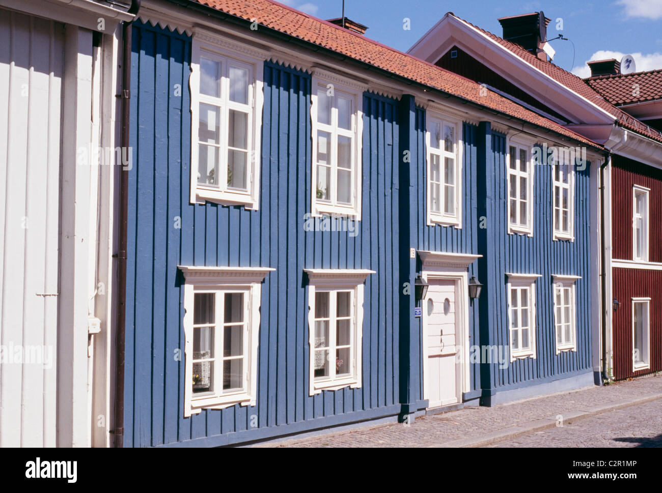 Row of colourful homes (blue, red) on street. Traditional style with timber cladding, 18th c. Vimmerby, Smaland. Stock Photo