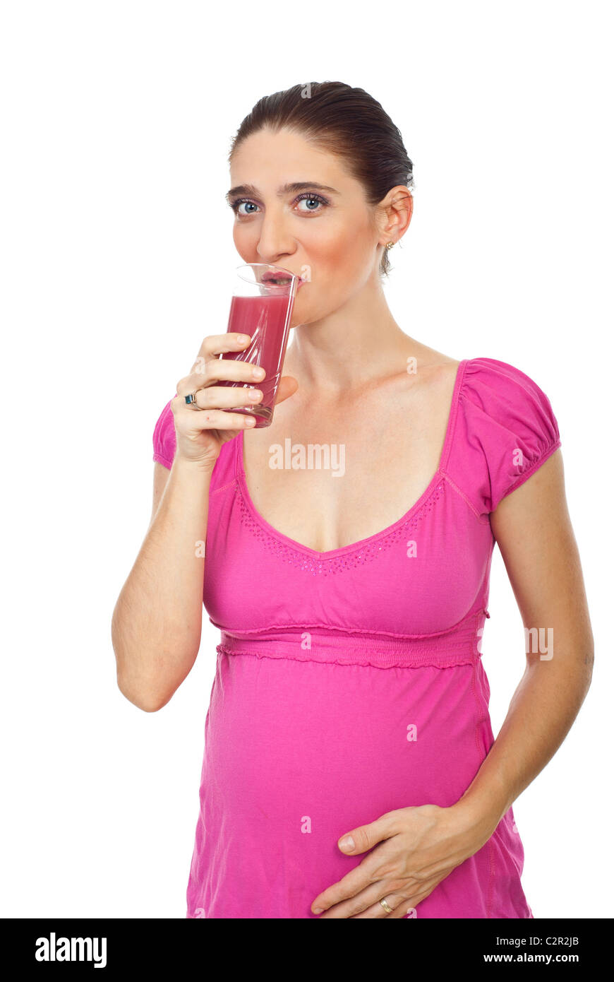 Pregnant woman with green eyes drinking strawberry juice and holding