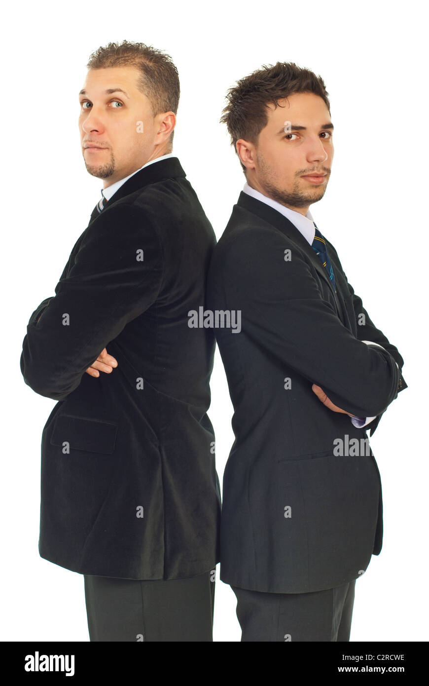 Two business men in suits standing with arms folded back to back ...