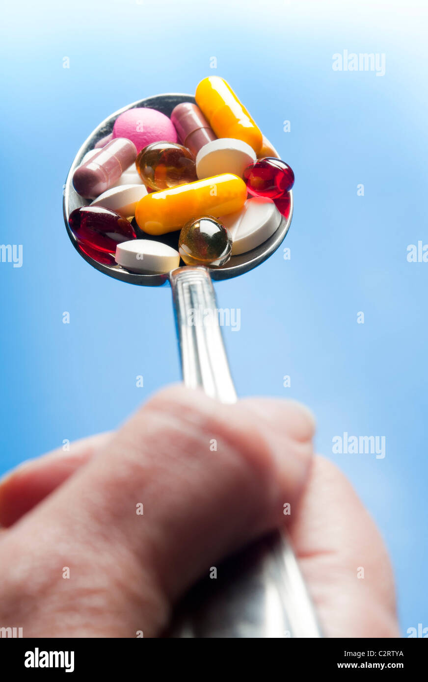 hand holding a spoon full of pills, medicinal drugs abuse concept Stock Photo