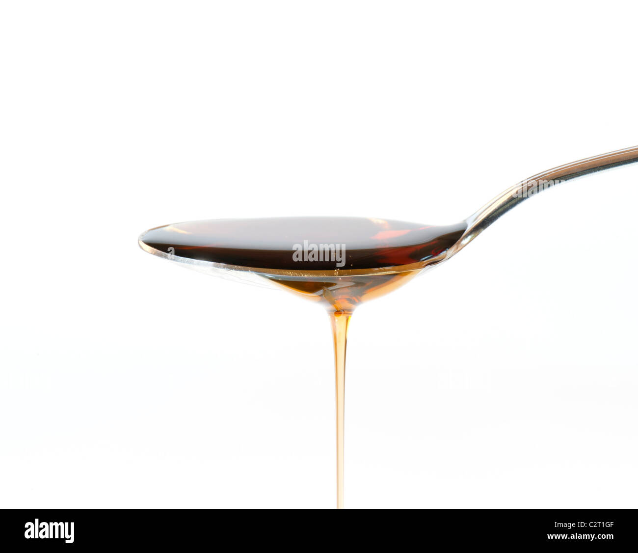 Maple Syrup Overflowing Off A Silver Dessert Spoon Stock Photo