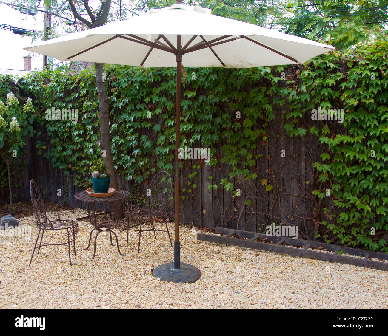 An umbrella with a table and chairs in a backyard Stock Photo