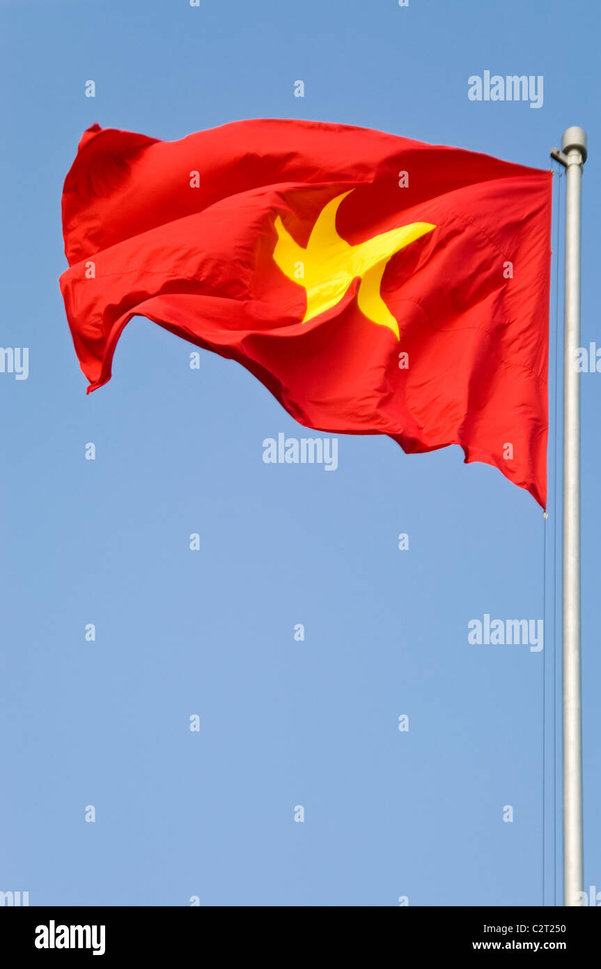 Vertical close up of the 'cờ đỏ sao vàng' (red flag with a yellow star) National flag of Vietnam since 1945, against blue sky. Stock Photo