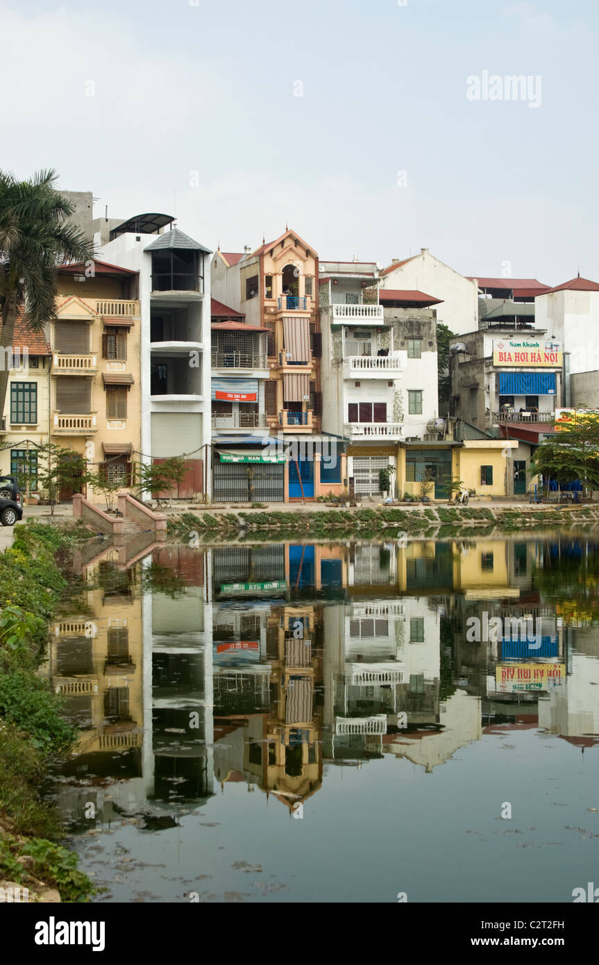 Vertical view of tall thin houses reflected in a lake in a suburban area of central Hanoi. Stock Photo