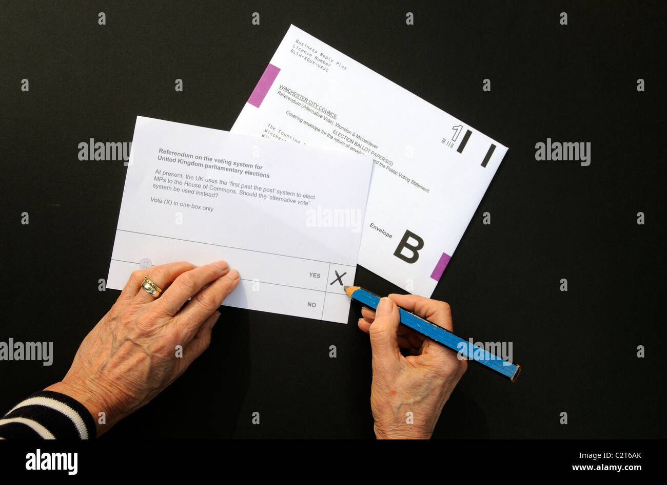 Referendum postal voting paper female hand puts a X in the Yes box Stock Photo