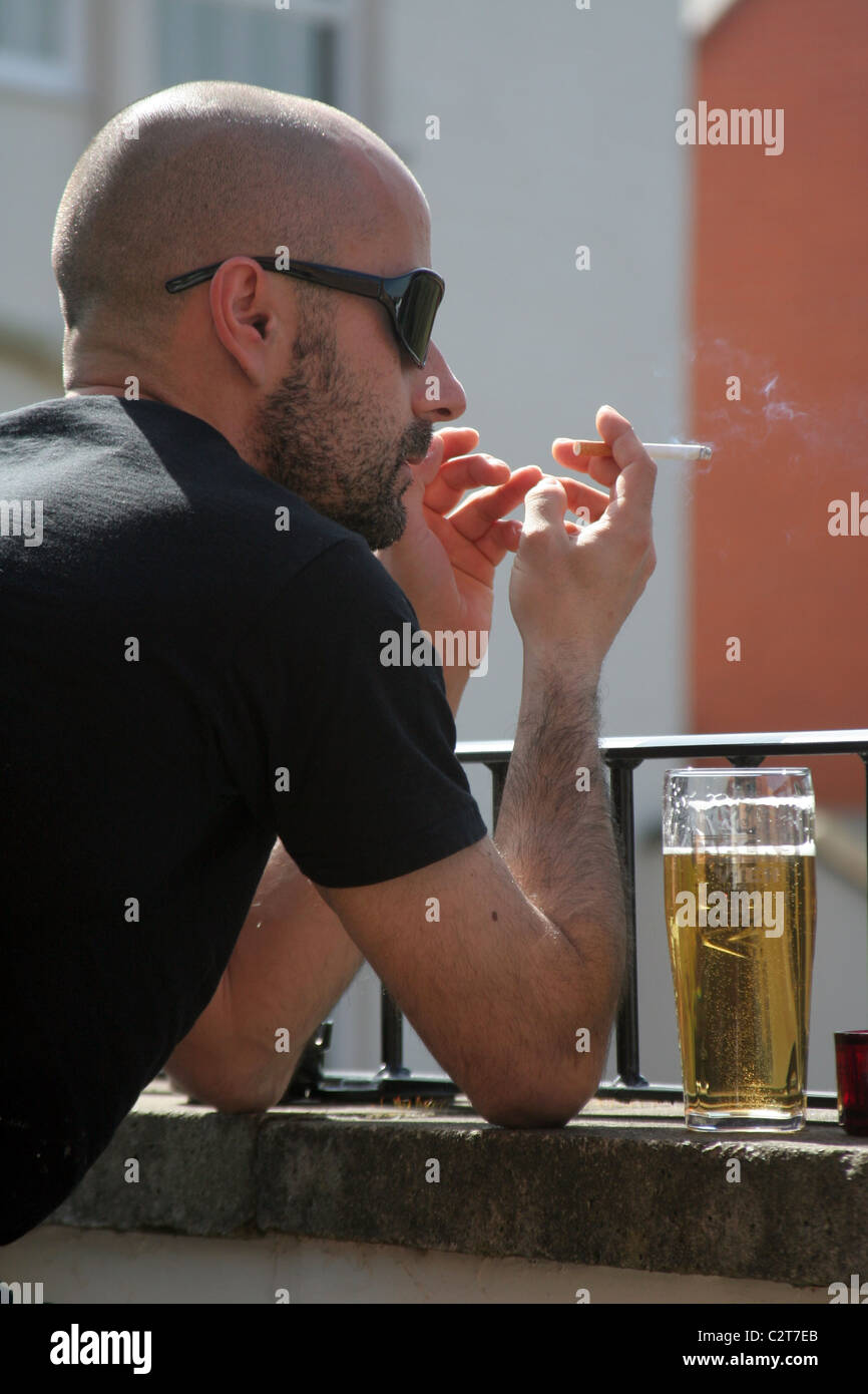 Young man smoking and drinking Stock Photo - Alamy