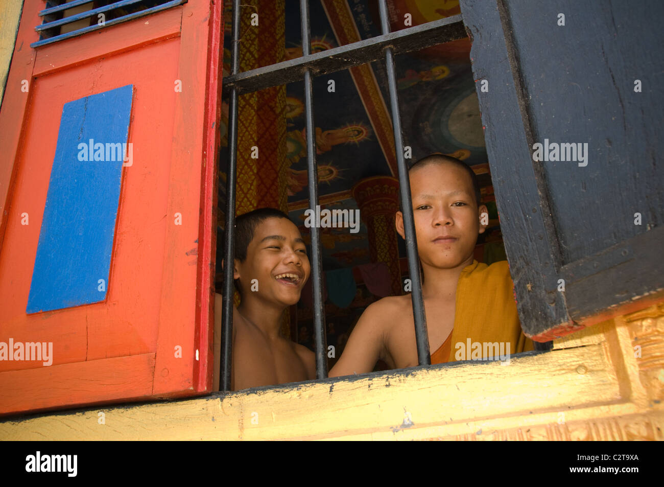 Angkor, Cambodia - July 2010, Cambodian kid monk and his friend at the Temple looking at the camera through a window. Stock Photo