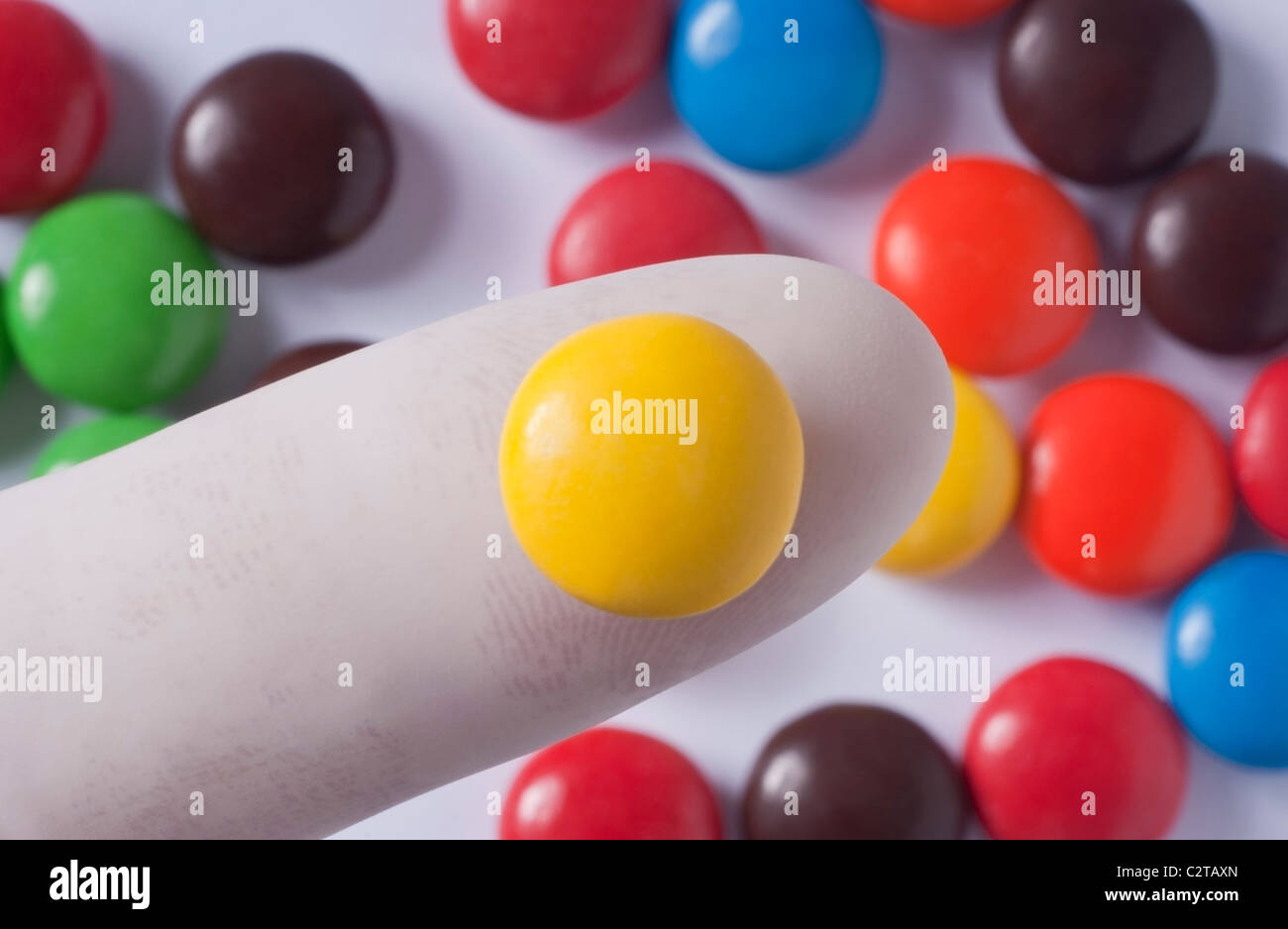 Gloved finger holding candy sold in the United States that contains Artificial Food Coloring that may cause ADHD in Children. Stock Photo